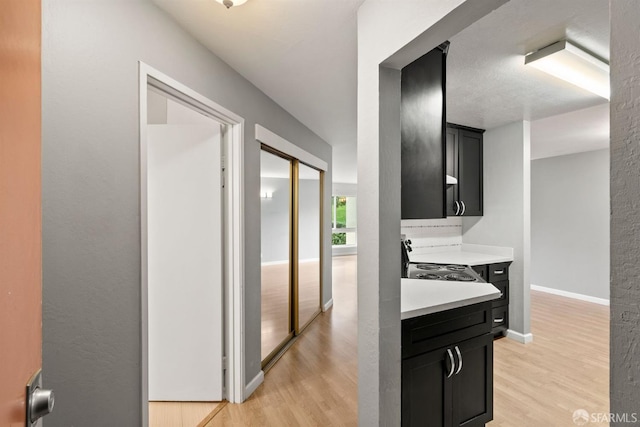 corridor featuring light wood-type flooring and baseboards