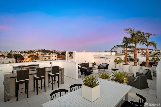 patio terrace at dusk featuring an outdoor living space and a bar