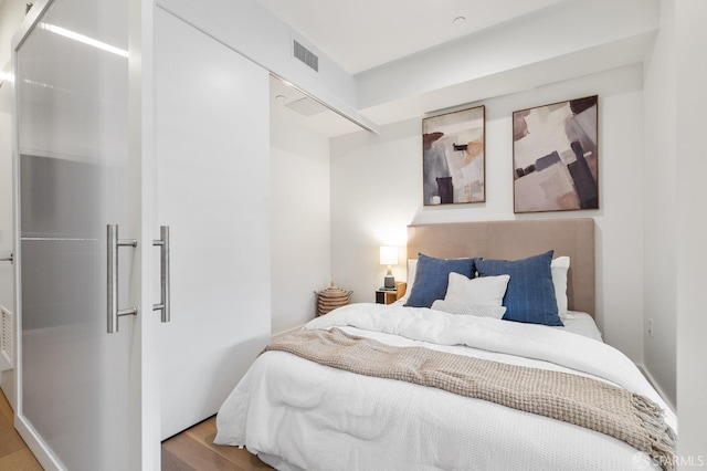 bedroom featuring wood finished floors and visible vents