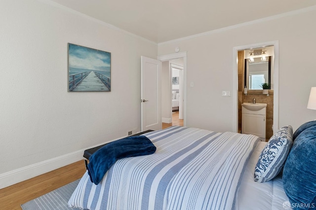 bedroom featuring wood-type flooring, sink, ensuite bathroom, and crown molding