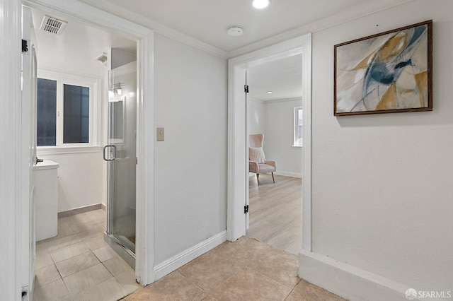 corridor with ornamental molding and light tile patterned floors