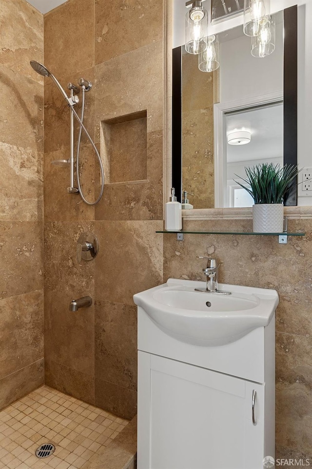 bathroom with vanity, tiled shower, and tile walls