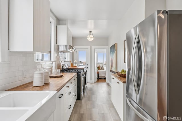 1371-1373 16th Ave, San Francisco, CA 94122 - kitchen with stainless steel appliances, white cabinets, backsplash, wall chimney exhaust hood, and butcher block counters
