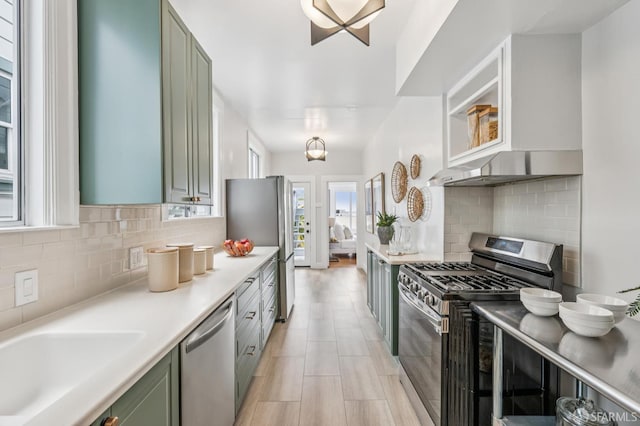 1371-1373 16th Ave, San Francisco, CA 94122 - kitchen featuring appliances with stainless steel finishes, green cabinetry, light countertops, decorative backsplash, and range hood