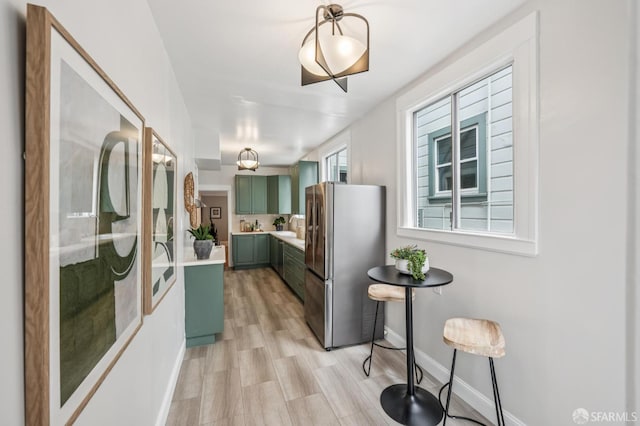 1371-1373 16th Ave, San Francisco, CA 94122 - kitchen with green cabinetry, freestanding refrigerator, light countertops, light wood finished floors, and decorative light fixtures