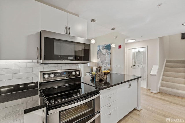 88 King St Unit 104, San Francisco, CA 94107 - kitchen featuring dark countertops, light wood-style floors, white cabinetry, stainless steel appliances, and pendant lighting
