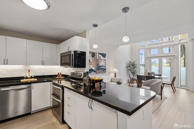 88 King St Unit 104, San Francisco, CA 94107 - kitchen with a peninsula, light wood-type flooring, white cabinets, appliances with stainless steel finishes, and decorative backsplash