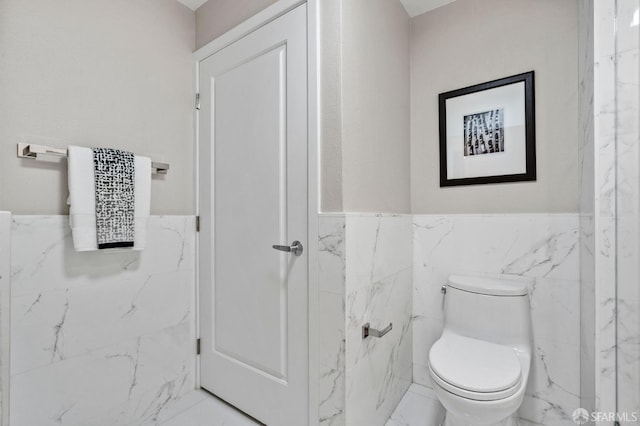 88 King St Unit 104, San Francisco, CA 94107 - bathroom featuring toilet, tile walls, marble finish floor, and a wainscoted wall