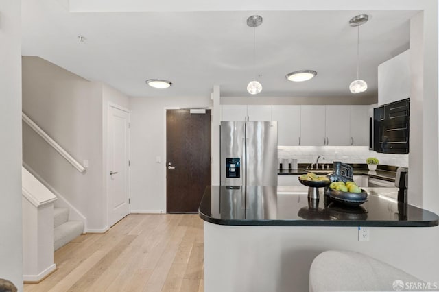 88 King St Unit 104, San Francisco, CA 94107 - kitchen featuring stainless steel fridge, a peninsula, light wood-style flooring, dark countertops, and decorative backsplash