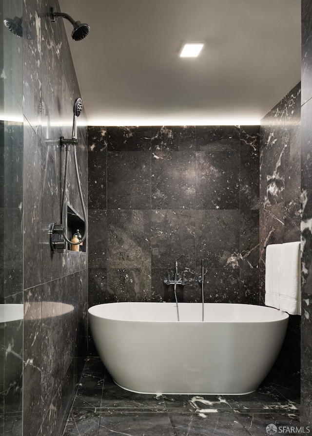 bathroom featuring a soaking tub, marble finish floor, and a tile shower