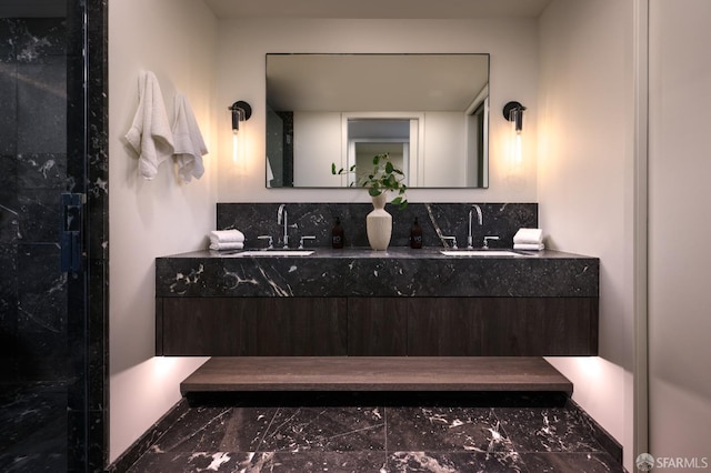 full bath with double vanity, marble finish floor, and a sink