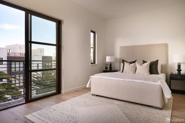 bedroom featuring multiple windows, baseboards, and wood finished floors