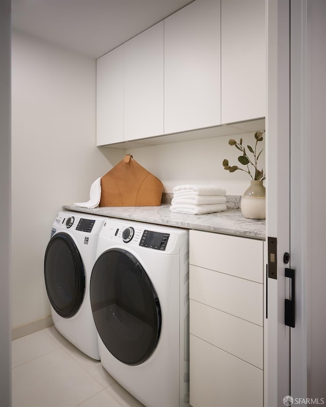 washroom featuring light tile patterned flooring, washing machine and clothes dryer, and cabinet space