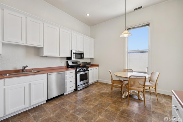 1695 Sutter St, San Francisco, CA 94109 - kitchen with appliances with stainless steel finishes, stone finish floors, white cabinets, hanging light fixtures, and recessed lighting