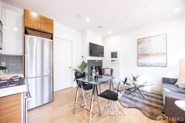 interior space featuring open floor plan, light countertops, backsplash, stainless steel refrigerator, and light wood finished floors