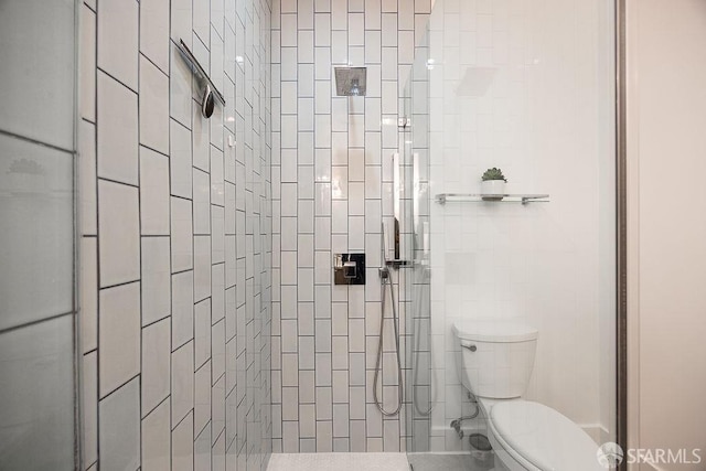 bathroom featuring a tile shower and toilet