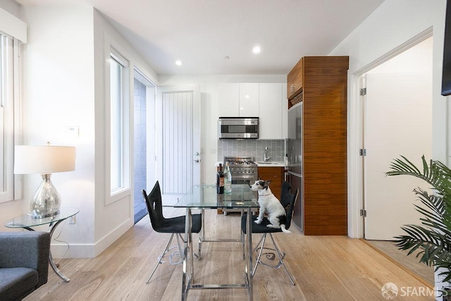 dining room with light wood-style floors, recessed lighting, and baseboards