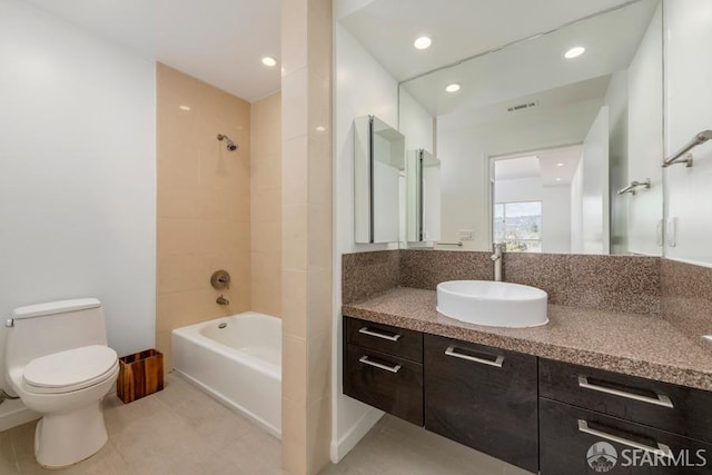 full bathroom featuring toilet, tiled shower / bath, vanity, and tile patterned floors