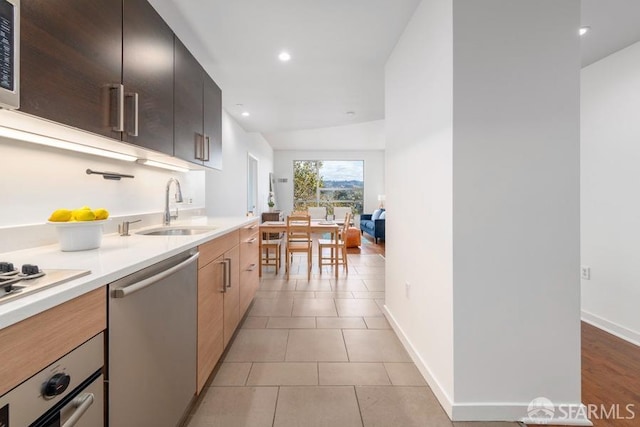 kitchen featuring sink, light tile patterned floors, appliances with stainless steel finishes, and lofted ceiling