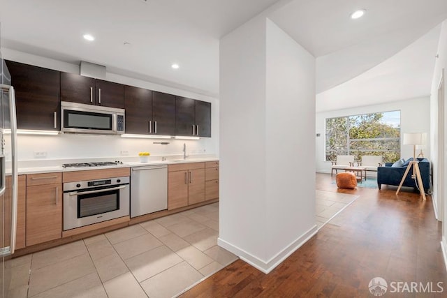 kitchen featuring appliances with stainless steel finishes, light hardwood / wood-style flooring, dark brown cabinetry, and sink