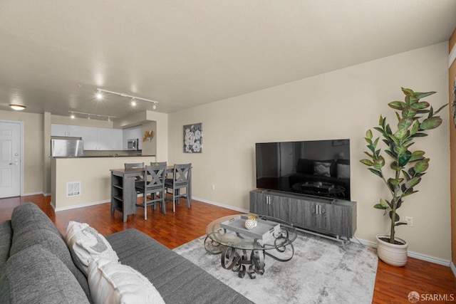 living room featuring wood finished floors, visible vents, and baseboards