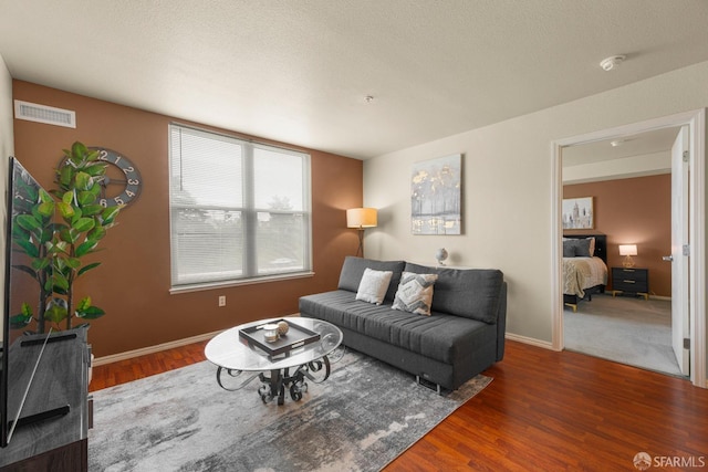 living area with wood finished floors, visible vents, and baseboards