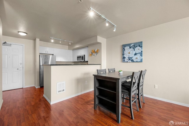 dining space featuring dark wood finished floors, baseboards, and visible vents