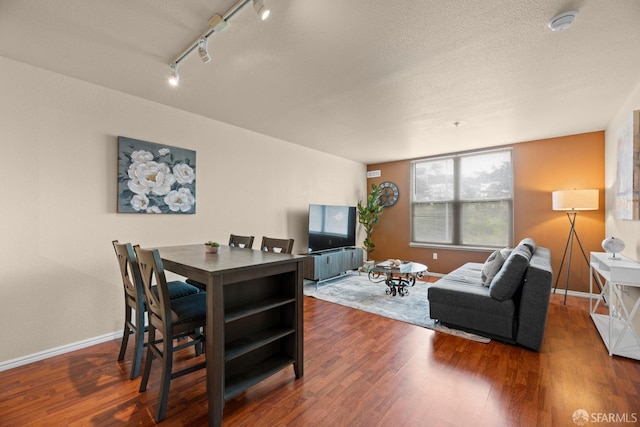 dining room with baseboards, a textured ceiling, wood finished floors, and rail lighting