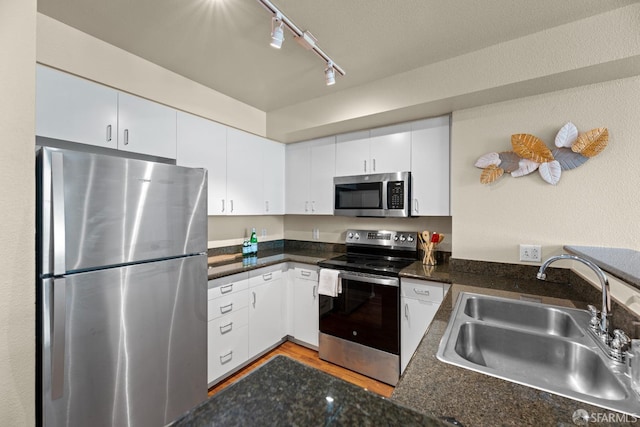 kitchen featuring a sink, stainless steel appliances, dark countertops, and white cabinetry