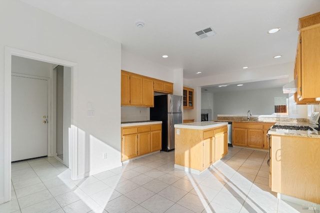 kitchen featuring sink, stainless steel refrigerator, a center island, light tile patterned flooring, and kitchen peninsula