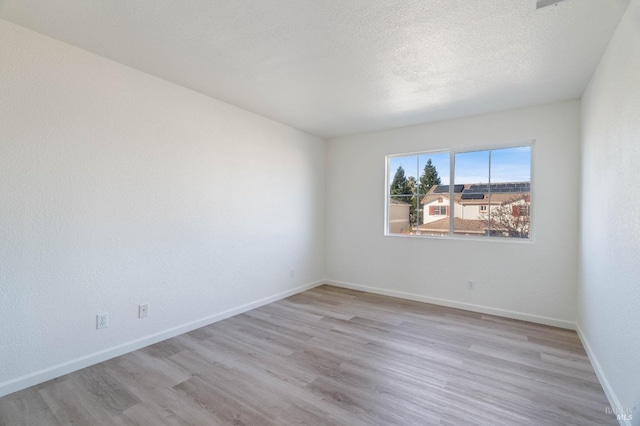 empty room featuring light hardwood / wood-style floors and a textured ceiling