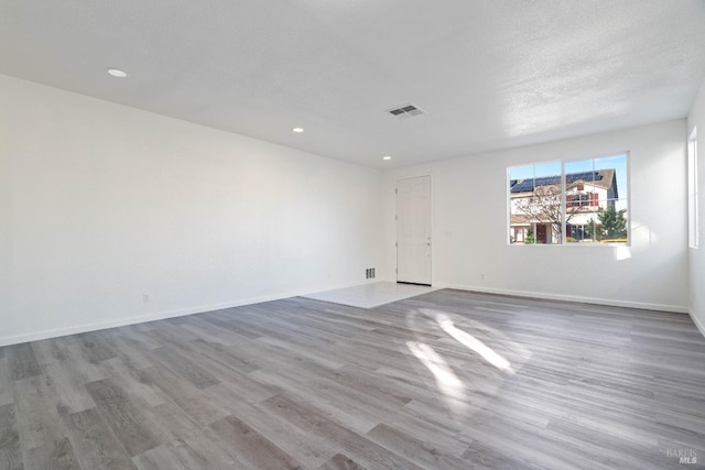 empty room featuring a textured ceiling and light hardwood / wood-style flooring