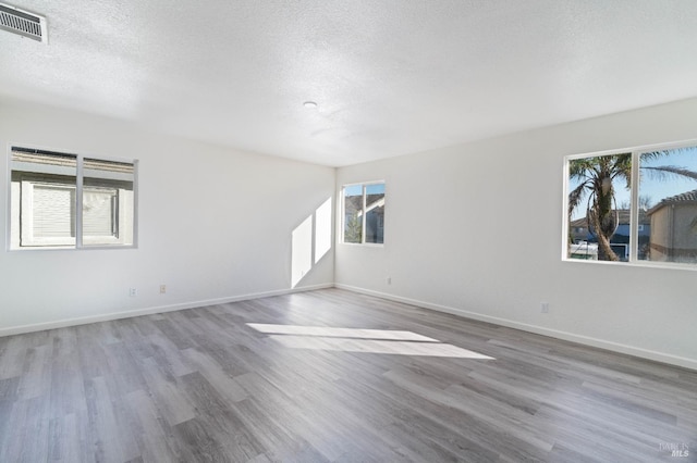 spare room featuring hardwood / wood-style floors and a textured ceiling