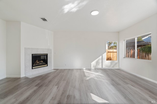 unfurnished living room featuring a tiled fireplace and light wood-type flooring