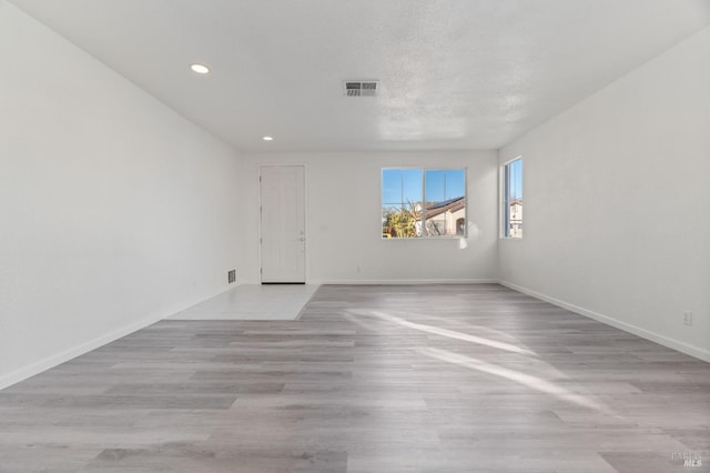 spare room with light hardwood / wood-style flooring and a textured ceiling