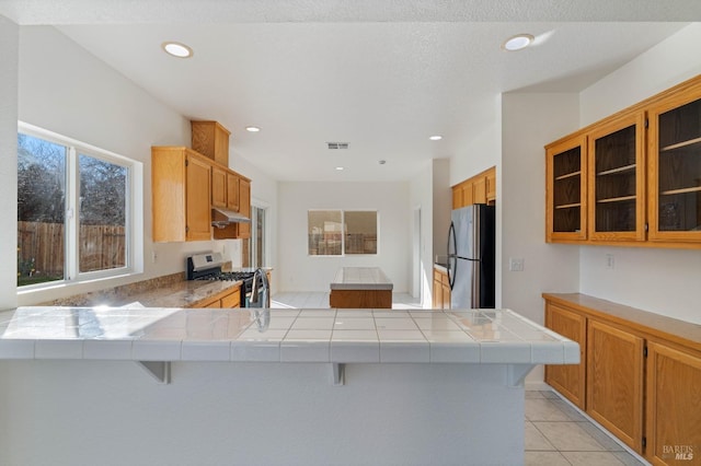 kitchen featuring a kitchen breakfast bar, tile countertops, stainless steel appliances, and kitchen peninsula