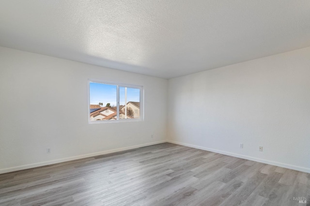 spare room with a textured ceiling and light hardwood / wood-style floors