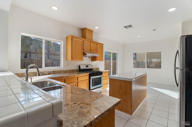 kitchen with a kitchen island, tile countertops, sink, light tile patterned floors, and stainless steel appliances