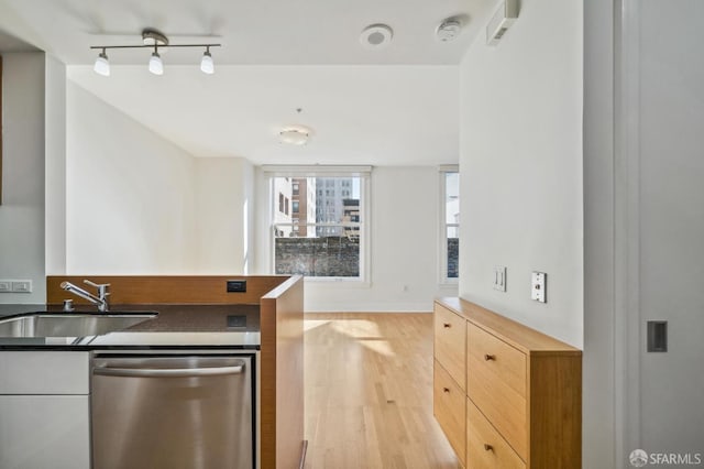 kitchen featuring track lighting, light hardwood / wood-style flooring, light brown cabinetry, sink, and stainless steel dishwasher