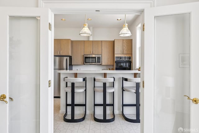 3364 21st St, San Francisco, CA 94110 - kitchen featuring stainless steel appliances, brown cabinets, a breakfast bar area, light countertops, and hanging light fixtures