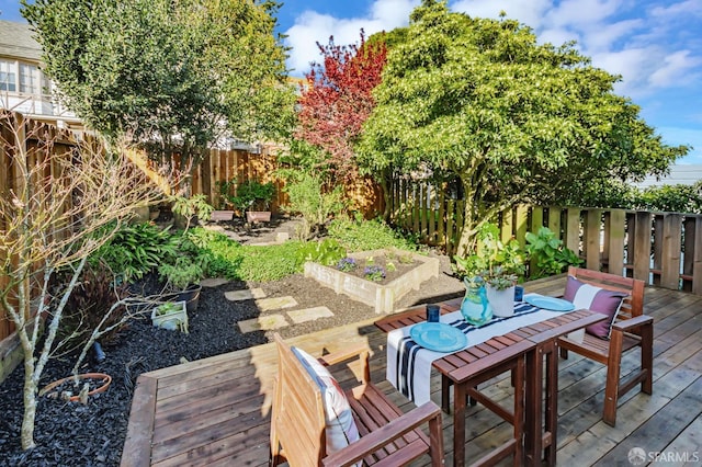 view of patio with a fenced backyard, a wooden deck, outdoor dining area, and a vegetable garden