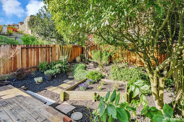 view of yard with a wooden deck, a vegetable garden, and a fenced backyard