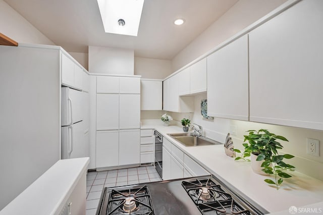 kitchen featuring white cabinetry, a skylight, freestanding refrigerator, and a sink