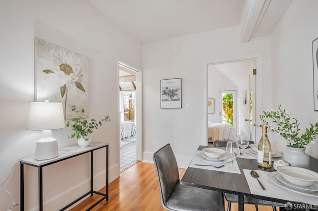 dining area with beamed ceiling and light wood finished floors