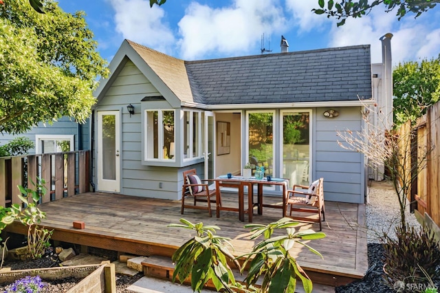 rear view of property featuring a deck and fence