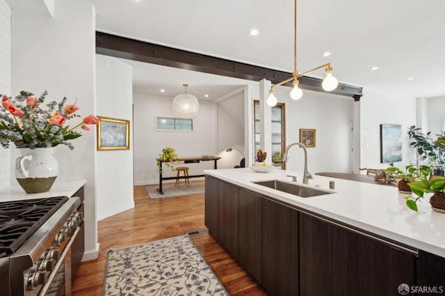 kitchen with hanging light fixtures, an inviting chandelier, stainless steel range with gas stovetop, and sink