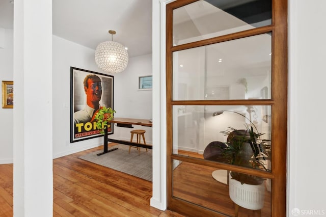 hall with hardwood / wood-style flooring and a notable chandelier