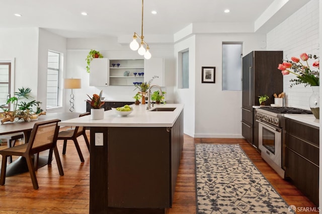 kitchen featuring high end stove, sink, dark hardwood / wood-style flooring, hanging light fixtures, and dark brown cabinets