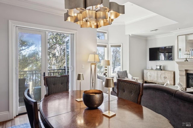 dining area with hardwood / wood-style flooring, ornamental molding, and a notable chandelier