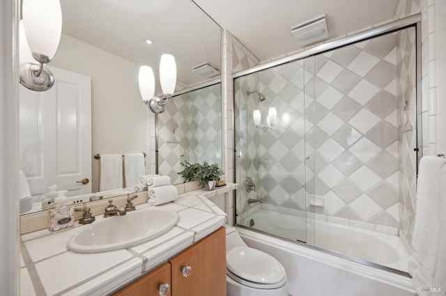 full bathroom featuring vanity, enclosed tub / shower combo, and toilet